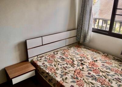 Cozy bedroom with floral bedspread and wooden side table