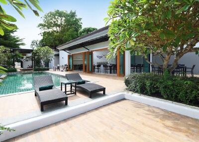 Outdoor seating area next to a swimming pool with greenery