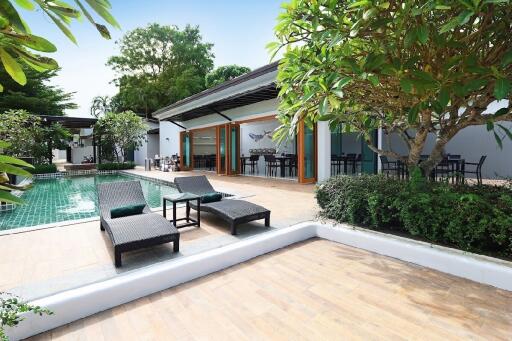 Outdoor seating area next to a swimming pool with greenery