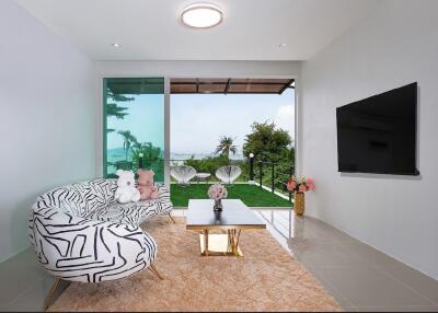 Modern living room with large window and a view, featuring unique patterned couch, coffee table, and wall-mounted TV