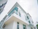 Modern white exterior of a two-story house with glass balconies