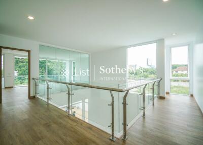 Spacious upper-level hallway with glass railings and wooden flooring