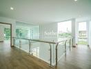 Spacious upper-level hallway with glass railings and wooden flooring