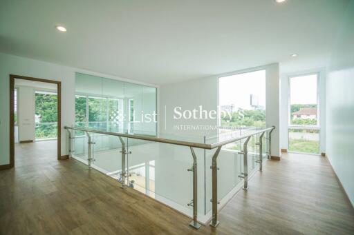 Spacious upper-level hallway with glass railings and wooden flooring