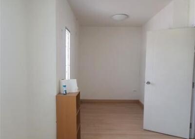 A minimalistic bedroom with wooden flooring and a small shelf unit