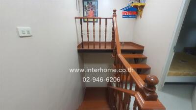 Staircase with wooden banister and small landing