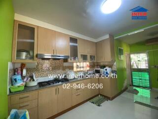 Modern kitchen with green walls, wood cabinets, and stainless steel appliances