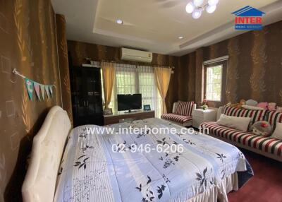 Spacious bedroom with large bed, seating area, and air conditioning