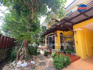 Front view of a yellow house with garden and covered porch