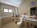 Bathroom with tiled walls, a toilet, a sink with a countertop, a mirror, and shelves with toiletries.