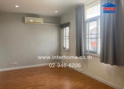 Unfurnished bedroom with wooden flooring, air conditioning, and large windows.