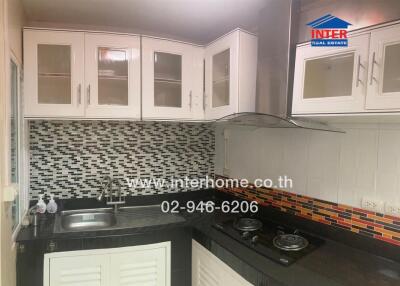 A modern kitchen with black countertops, white cabinets, and a tiled backsplash.