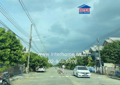 Street view of residential neighborhood with houses and trees.