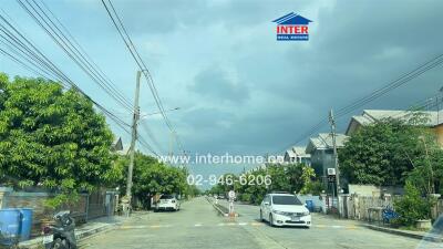 Street view of residential neighborhood with houses and trees.