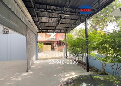 Covered parking area with view of garage door, greenery, and neighboring houses