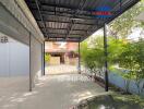 Covered parking area with view of garage door, greenery, and neighboring houses