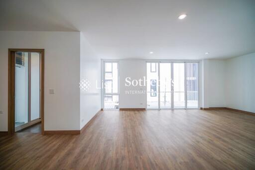 Spacious and well-lit living room with wooden flooring and large windows