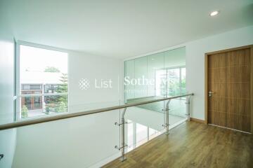 Modern hallway with wooden flooring, glass railing, and a wooden door