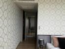 bedroom with patterned wallpaper, bed, nightstand, lamp, and hallway view