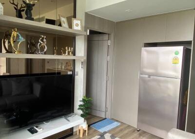 Modern living area with TV, shelves, and refrigerator