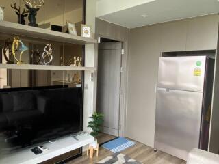 Modern living area with TV, shelves, and refrigerator