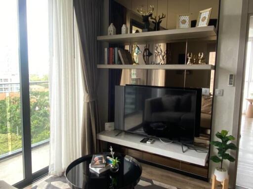 Modern living room with large window, TV, and decorative shelves