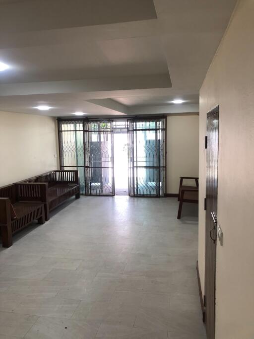 Spacious main living room with tiled flooring, wood furniture and large glass door leading outside