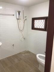 Bathroom with tiled walls and floor, showerhead, and a toilet