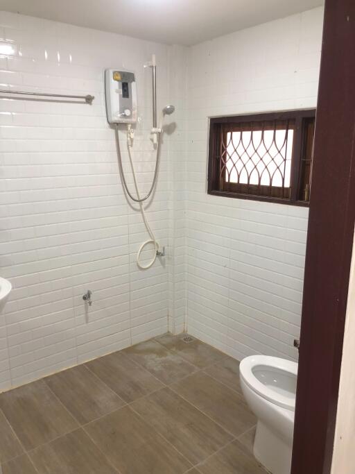 Bathroom with tiled walls and floor, showerhead, and a toilet