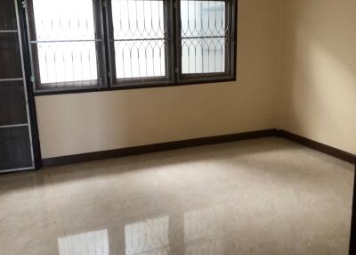 Spacious empty living room with tiled floor and barred windows