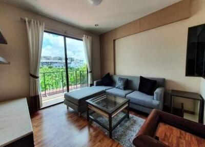 Living room with a gray sofa, glass table, and large window with a balcony view