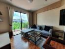 Living room with a gray sofa, glass table, and large window with a balcony view