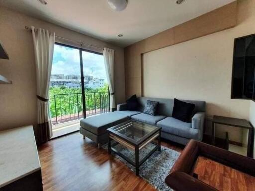 Living room with a gray sofa, glass table, and large window with a balcony view