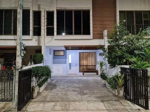 Front view of a modern townhouse with a driveway and gated entrance