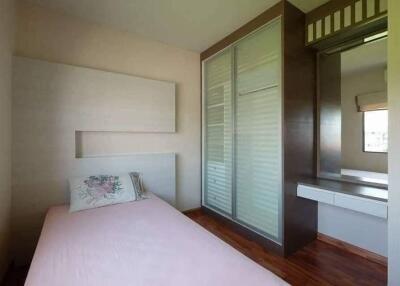 Small bedroom with pink bedding and built-in wardrobe