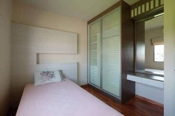 Small bedroom with pink bedding and built-in wardrobe