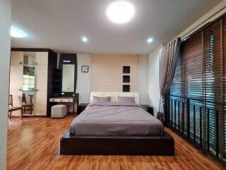 Spacious bedroom with wooden flooring and modern decor.