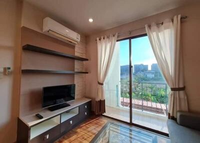 Bright living room with a TV and glass doors leading to a balcony