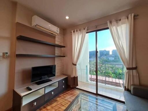 Bright living room with a TV and glass doors leading to a balcony