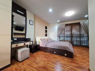 Modern bedroom with wooden flooring, large bed, and built-in furniture