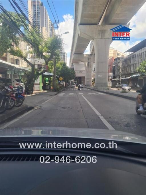 Street view with elevated train tracks and surrounding buildings