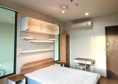 Modern bedroom with wooden flooring, bed, and study area