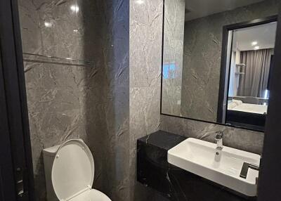 Modern bathroom with marble walls and a white toilet and sink