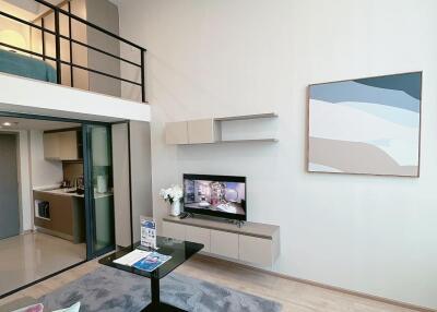 Modern living area with a mezzanine, television, and kitchen in the background