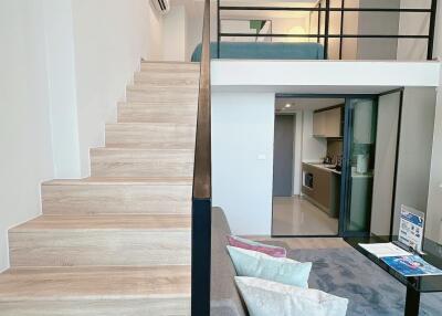 Loft-style living room and kitchen area with wooden stairs