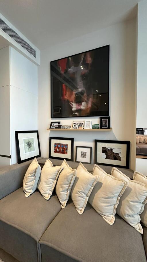 Modern living room with artwork on wall and numerous large cushions on the sofa