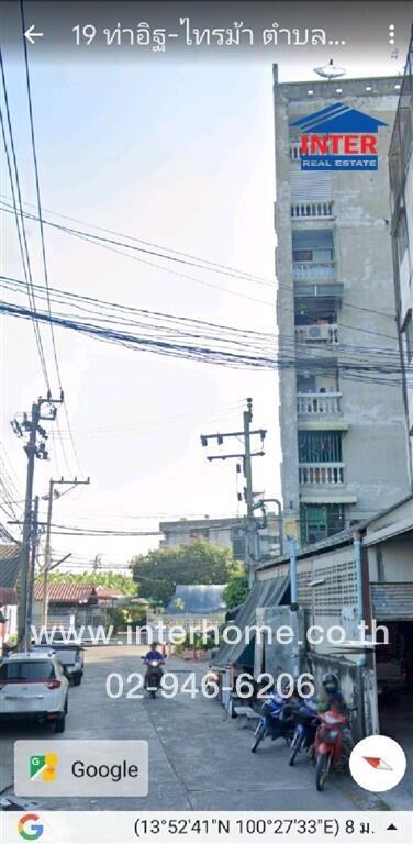 Street view of a building with visible balconies, electrical poles, and motorcycles parked on the street.