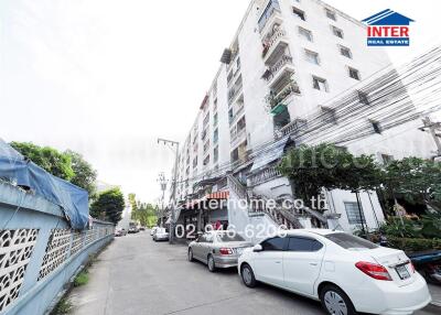 Exterior view of a multi-story apartment building with parked cars