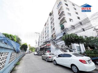 Exterior view of a multi-story apartment building with parked cars