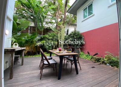 Outdoor dining area with table and chairs, surrounded by greenery